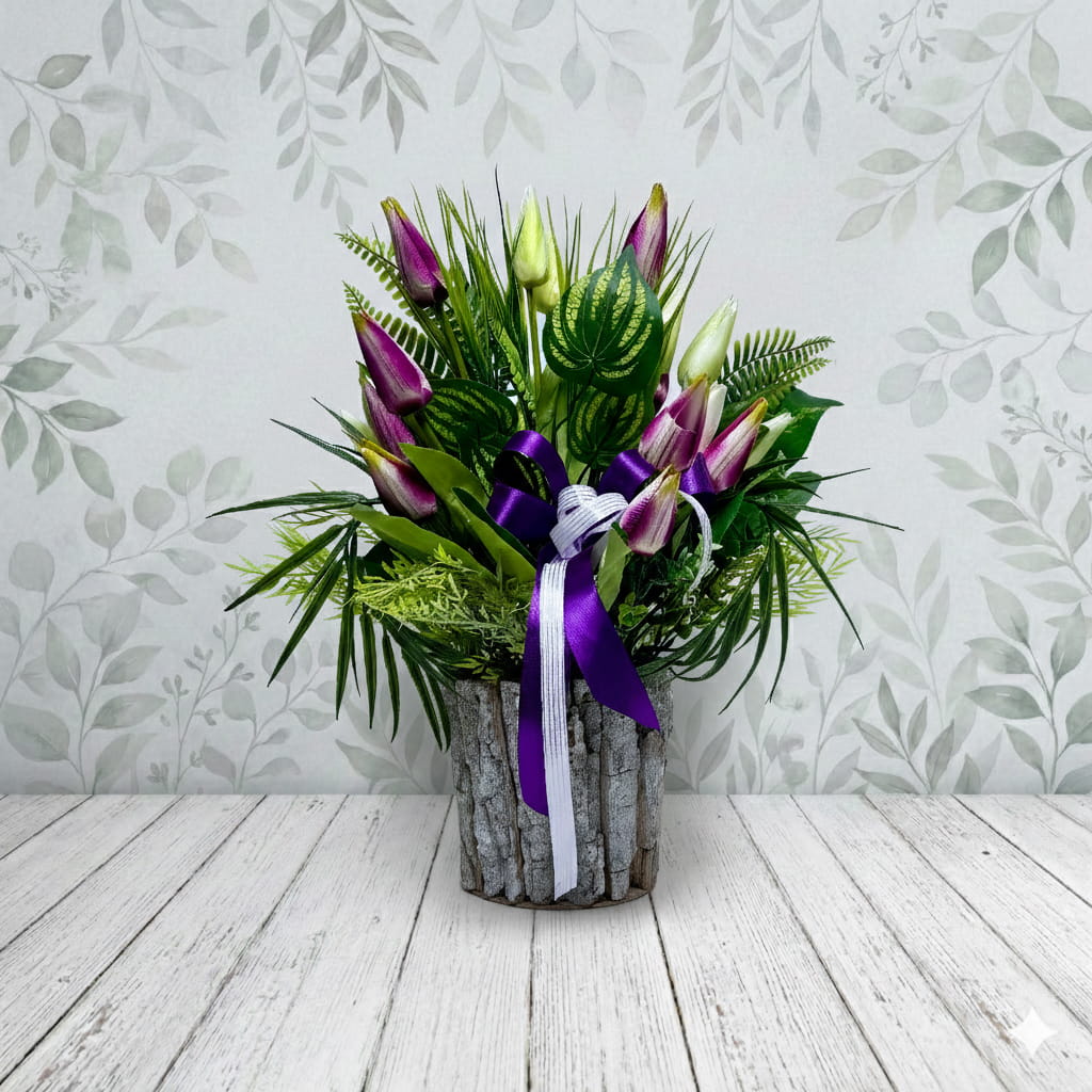 Wiosenna dekoracja nagrobna w okrągłej donicy wykonanej z jasnego drewna. Kompozycję tworzą liczne tulipany w dwóch kolorach: głębokiego fioletu oraz jasnego kremu. Kwiaty są rozmieszczone na różnych wysokościach, otoczone smukłymi, zielonymi liśćmi tulipanów oraz szerszymi liśćmi u podstawy. Całość tworzy gęsty, wysoki bukiet. Donica jest dociążona masą betonową, co zapewnia stabilność na pomniku. Wymiary: wysokość 50 cm, średnica 40 cm.